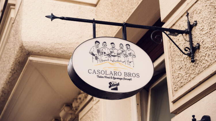 Hanging sign of Casolaro Bros showing the illustrated founders and Italian Food and Beverage Concept branding.