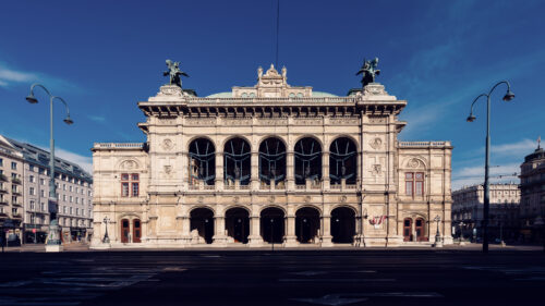 Frontale Gesamtansicht der Fassade der Wiener Staatsoper mit Pegasus-Statuen vor tiefblauem Himmel