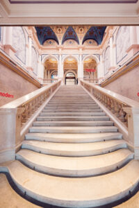 Marble staircase inside Albertina Modern, viewed from below with blue and gold ceiling details above.