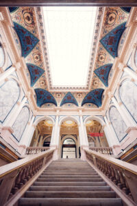 Upward view of the Künstlerhaus staircase hall with its elaborate blue, gold, and terracotta ceiling vault.