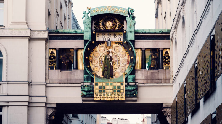 Front view of the Ankeruhr at Hoher Markt, showing the ornate clock face with gold details and two moving historical figures mid-parade.