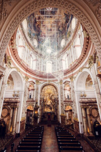 The grand interior of St. Charles Church (Karlskirche), with its impressive domed ceiling adorned with frescoes and gold detailing.