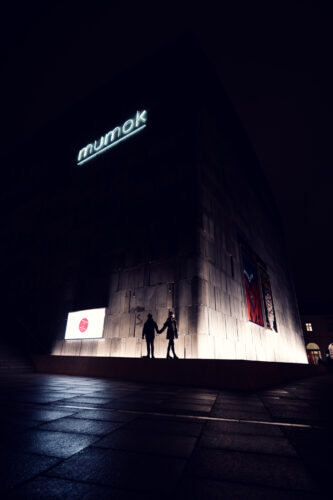 Dramatic evening scene of MUMOK's basalt cube architecture in MuseumsQuartier Vienna.