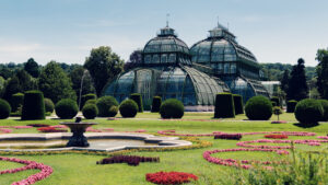 Panoramic view of the Palm House Schönbrunn rising behind a carpet of seasonal blooms.