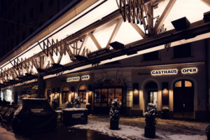 Snow-dusted entrance of Plachuttas Gasthaus zur Oper on a winter evening.