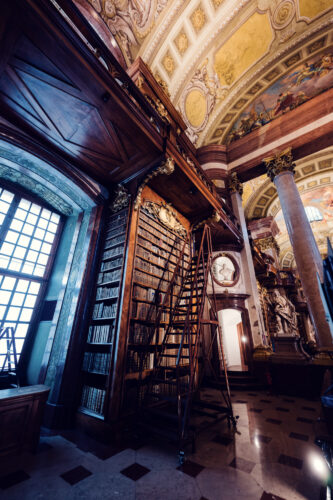 Centuries-old leather-bound volumes lining the towering wooden shelves of the Prunksaal.
