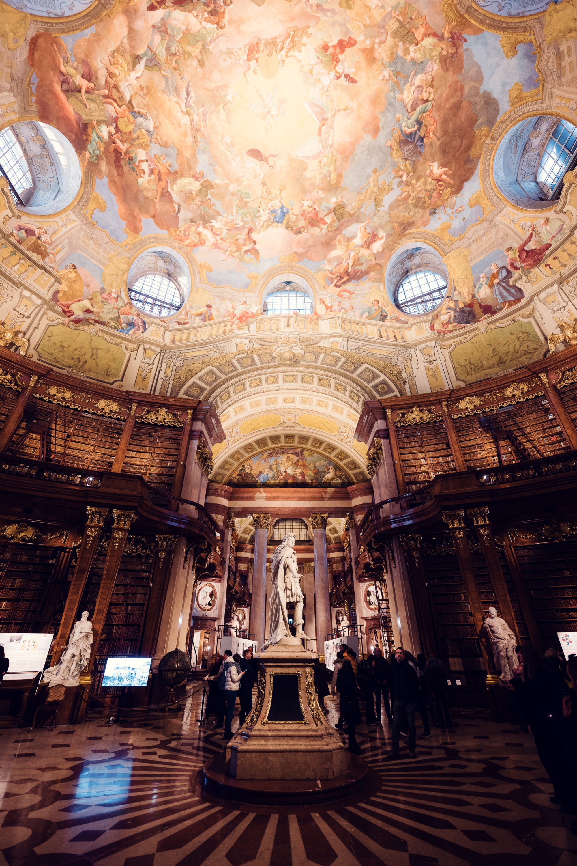 Central aisle of the Prunksaal with marble columns framing the hall of the Austrian National Library.