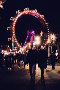 Adriana and Mario silhouetted against the illuminated Giant Ferris Wheel (Wiener Riesenrad) at night.