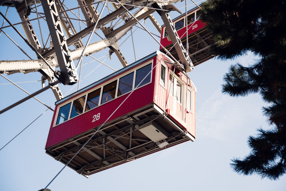 The Riesenrad towering against cotton-candy clouds, its red cabins providing pops of color in the dreamy sky.