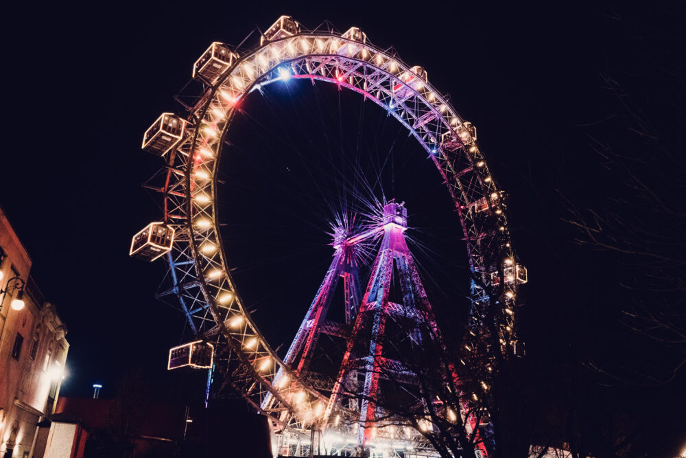 Night view of the Riesenrad, its illuminated cabins creating circles of light against Vienna's dark sky.