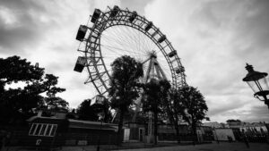 Iconic Giant Ferris Wheel (Wiener Riesenrad) silhouetted against a dramatic Viennese sky, with moody clouds creating a cinematic backdrop.