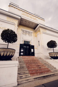 Detail of the Vienna Secession Building facade showing the contrast between the simple white walls and decorative Art Nouveau elements.