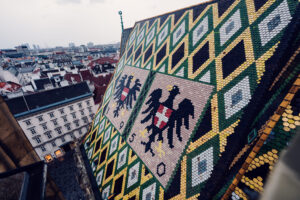 Colorful mosaic roof of St. Stephen's Cathedral, its 230,000 glazed tiles forming the double-headed eagle and Vienna's coat of arms.