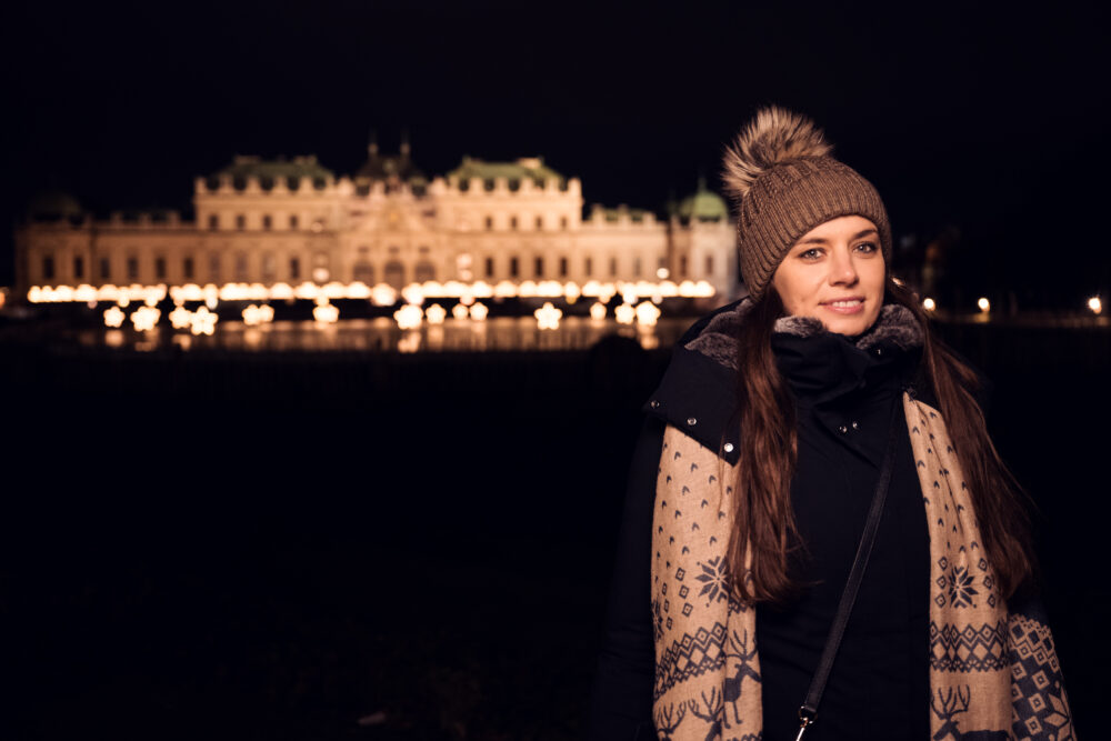 Enchanting winter moment at Upper Belvedere, where a girl poses against the illuminated baroque facade.