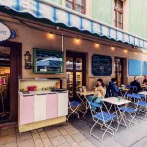Outdoor seating area in front of Vollpension with colorful chairs and tables.