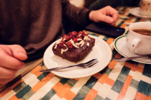 A slice of rich chocolate cake topped with cherries and almond slivers, served at Vollpension.