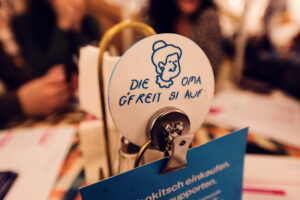 A small table sign at Vollpension with an illustration of a smiling grandma and the message, "Die Oma gfreit si auf!" ("Grandma is looking forward to seeing you!").
