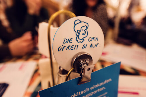 A small table sign at Vollpension with an illustration of a smiling grandma and the message, "Die Oma gfreit si auf!" ("Grandma is looking forward to seeing you!").