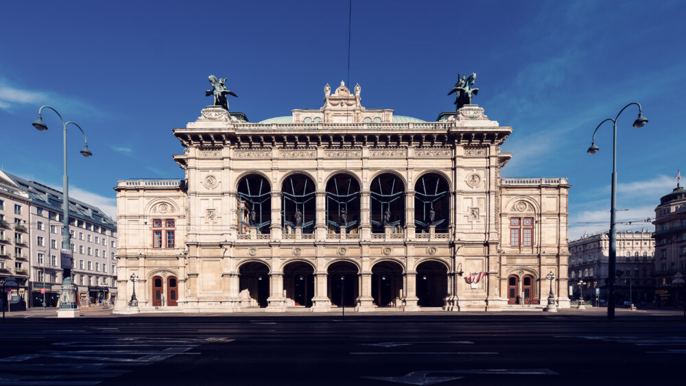 Vienna State Opera gleaming in bright sunlight, its Neo-Renaissance facade showcasing intricate architectural details perfect for photography.