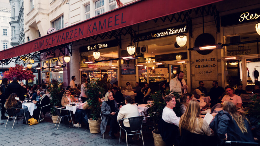 A lively street scene in front of the Viennese restaurant Zum Schwarzen Kameel.