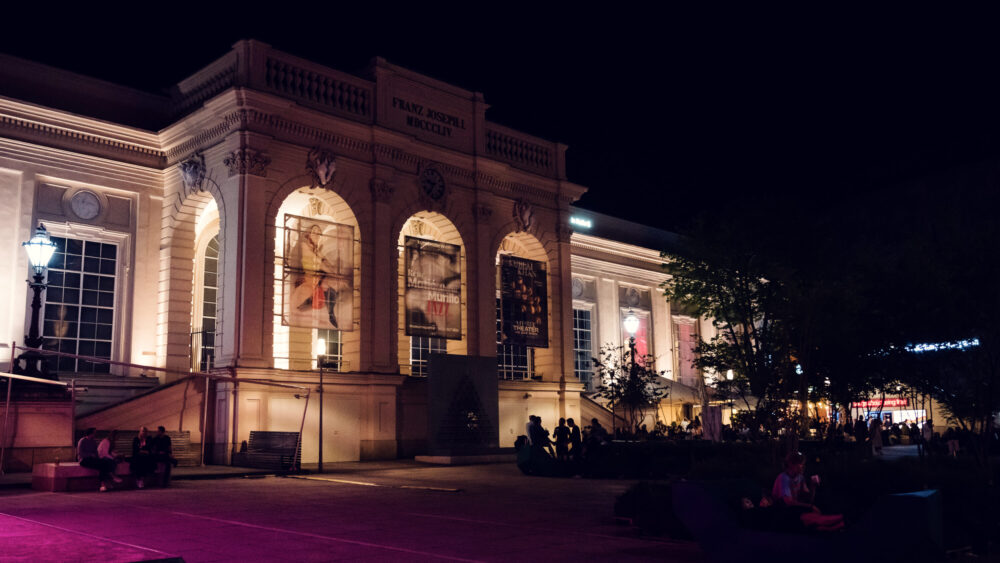 Evening social scene at MuseumsQuartier's outdoor spaces featuring illuminated cultural institutions.
