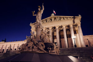 Fuente de Palas Atenea y edificio del Parlamento iluminado de noche en Viena.