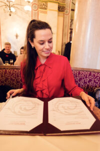 Adriana consulta il menu al Café Central, seduta in una delle panche in velluto.