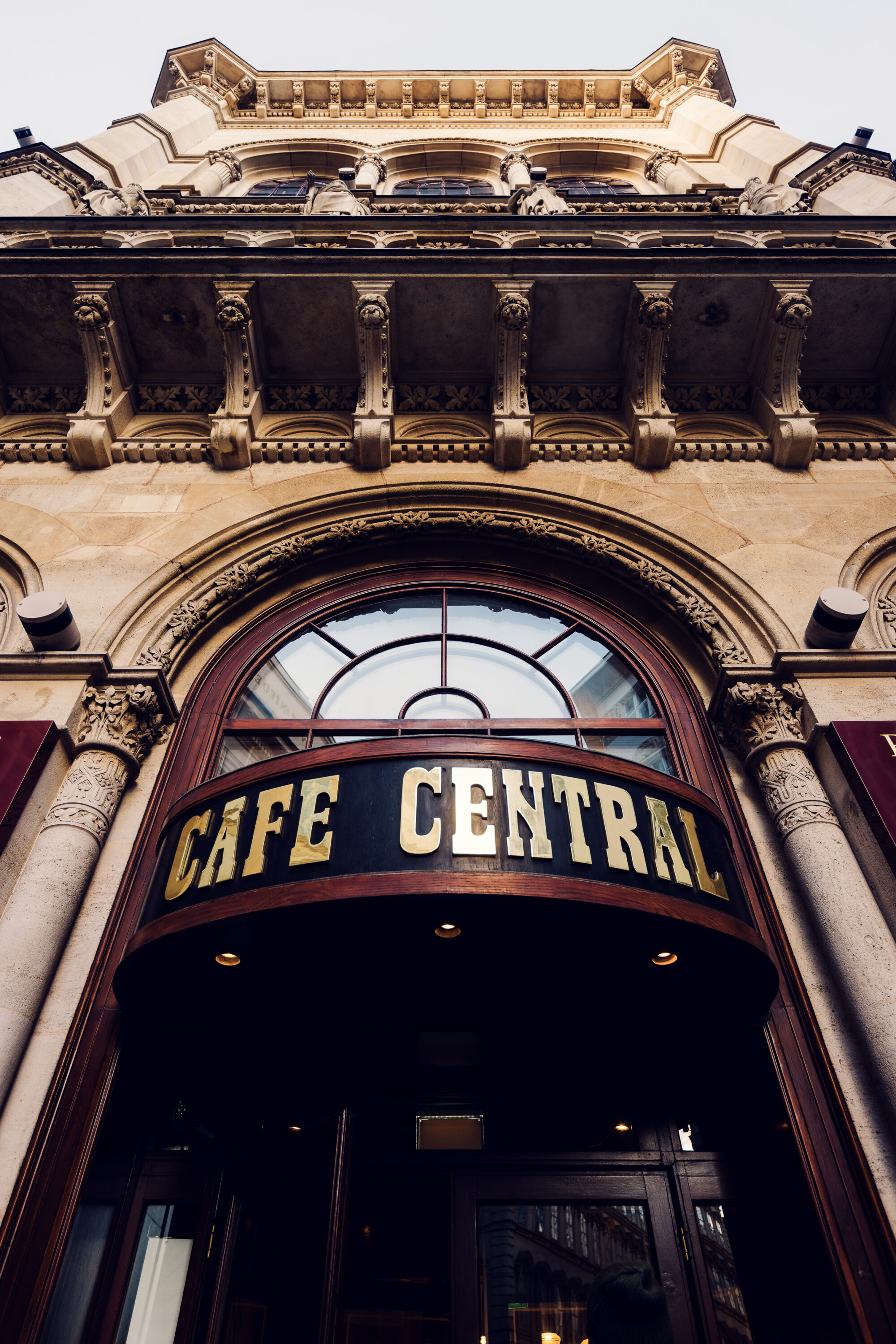 Primo piano dell'insegna del Café Central con lettere dorate su una tettoia scura.