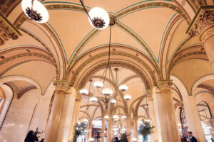 Soffitto a volta con archi dipinti e lampade a sospensione all'interno del Café Central.