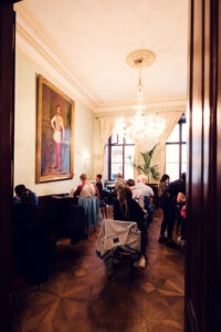 Vue sur une salle annexe du Café Demel avec une grande peinture à l'huile, parquet et clients attablés.
