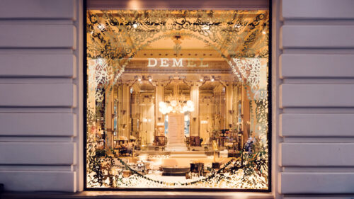 Decorated shop window of Café Demel with a view into the illuminated interior.