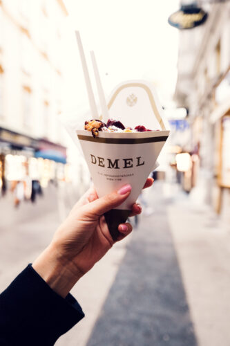Kaiserschmarrn to go in a branded Demel cone held on Kohlmarkt in Vienna.