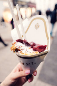 Gros plan d'un Kaiserschmarrn à emporter avec compote de fruits rouges et sucre glace dans un cornet Demel.