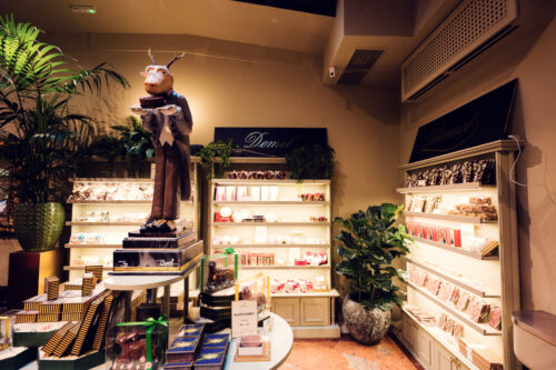 Espace chocolaterie du Café Demel avec une figurine décorative et des étagères de pralinés.