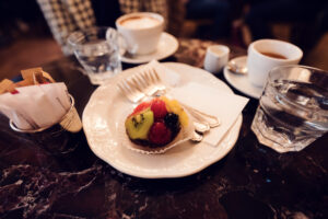 Tartelette aux fruits frais servie avec café et eau sur une table en marbre au Café Demel.