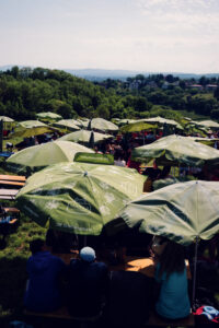Guests relaxing in the shade at Mayer am Nussberg with wine glasses on the table.