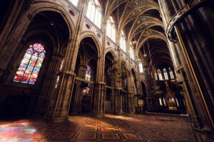 Interior of Votivkirche Vienna (Votive Church) with soaring ribbed vaults and neo-Gothic columns stretching 30 meters high, creating a dramatic vertical space.