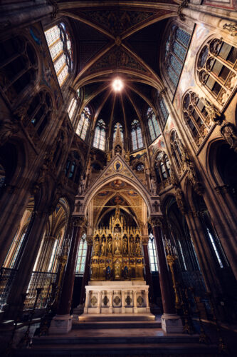Maître-autel orné de la Votivkirche de Vienne, avec sculptures en pierre, dorures et statues religieuses sous la voûte du chœur.