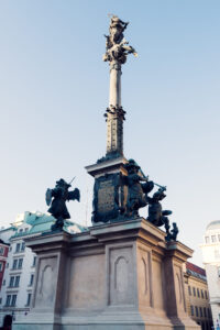 Close-up view of the Marian Column am Hof from below, showing the bronze sculptures at the base and the Virgin Mary statue on top.
