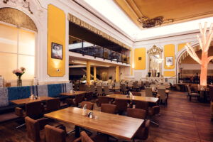 Spacious dining hall with gallery level and tree-shaped light fixtures at Brandauer's Schlossbräu.