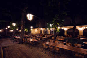 Empty beer garden with wooden tables and warm lantern light at Brandauer's Schlossbräu.