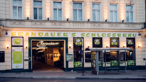 Exterior view of Brandauer's Schlossbräu with green lettering on the facade in Hietzing.