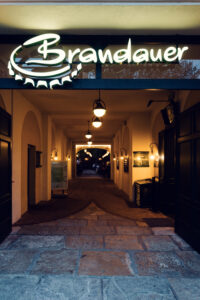 Lit Brandauer logo above the cobblestone passage leading to the beer garden.