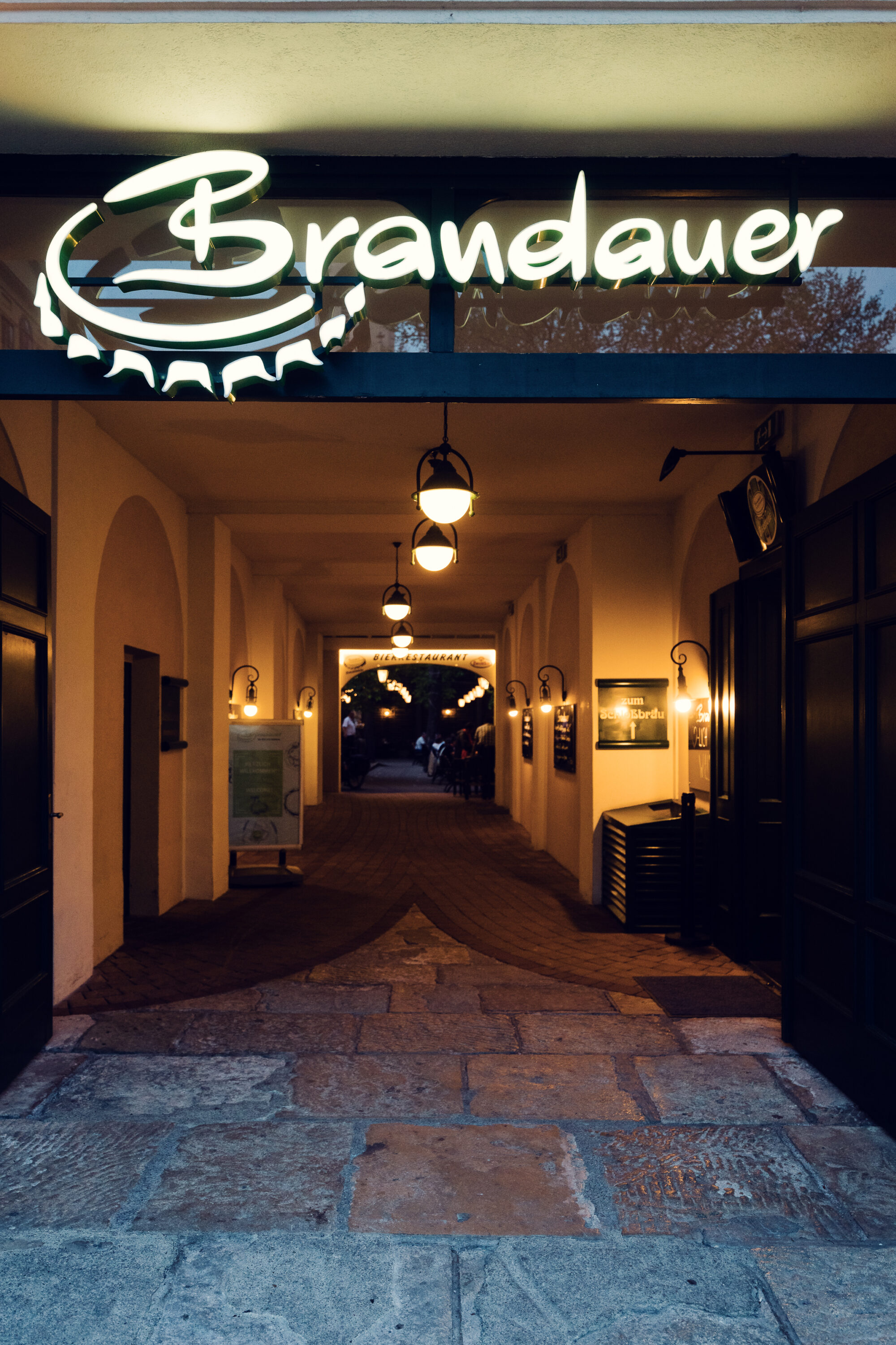Lit Brandauer logo above the cobblestone passage leading to the beer garden.