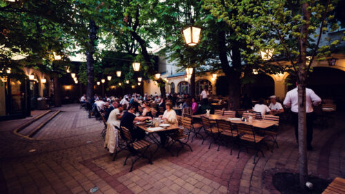 Guests dining in the tree-shaded courtyard beer garden at Brandauer's Schlossbräu.