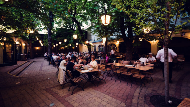 Guests dining in the tree-shaded courtyard beer garden at Brandauer's Schlossbräu.