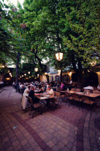 Evening view of the spacious beer garden under chestnut trees at Brandauer's Schlossbräu.
