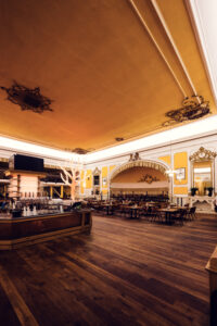 Grand ballroom-style dining hall with golden ceiling and central bar at Brandauer's Schlossbräu.