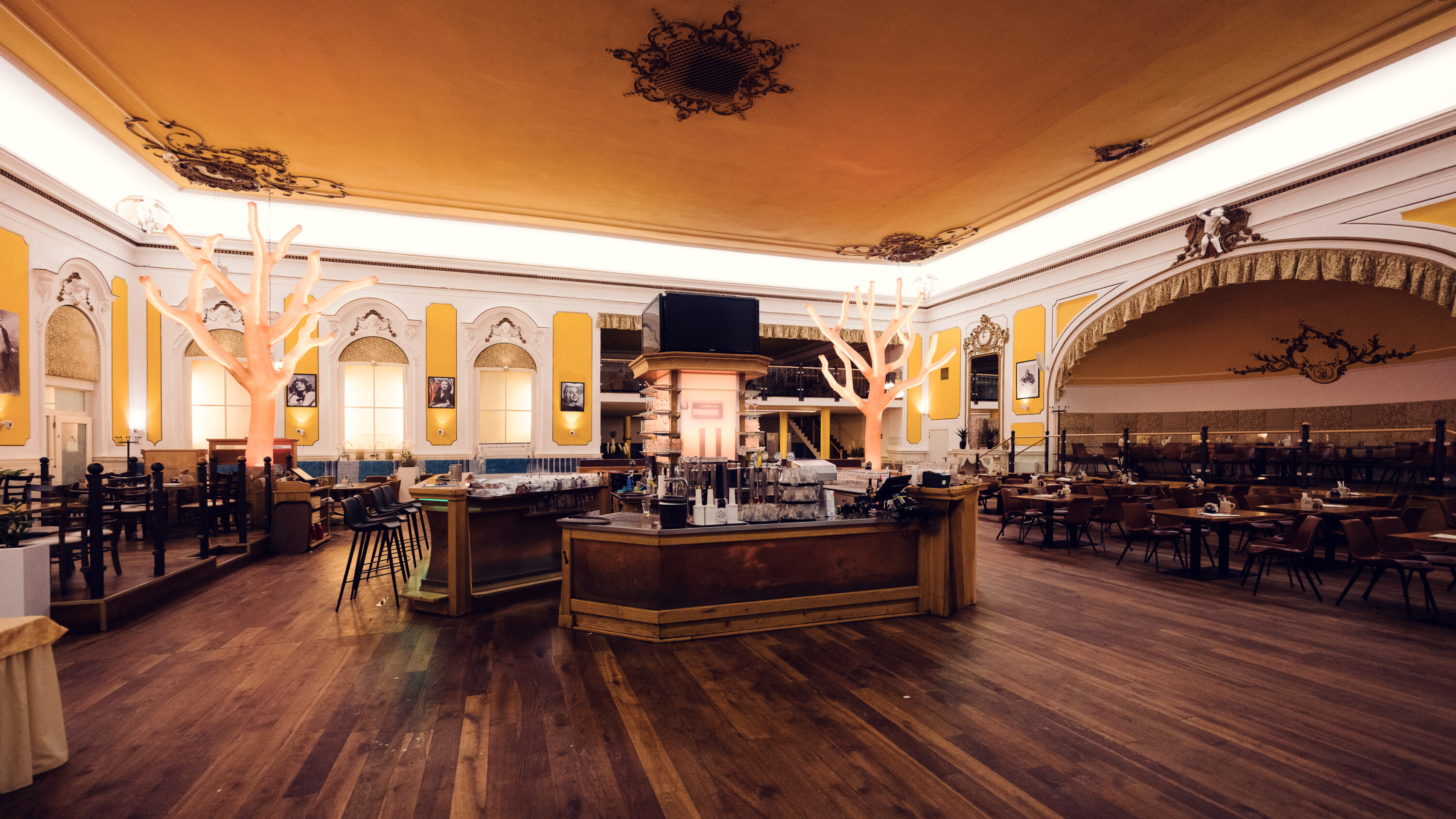 Wide-angle view of the ornate main hall with decorative tree sculptures at Brandauer's Schlossbräu.