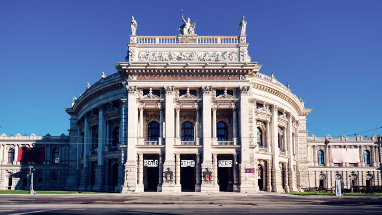 Front view of the Burgtheater on the Ringstrasse in Vienna with its curved wings and columns.